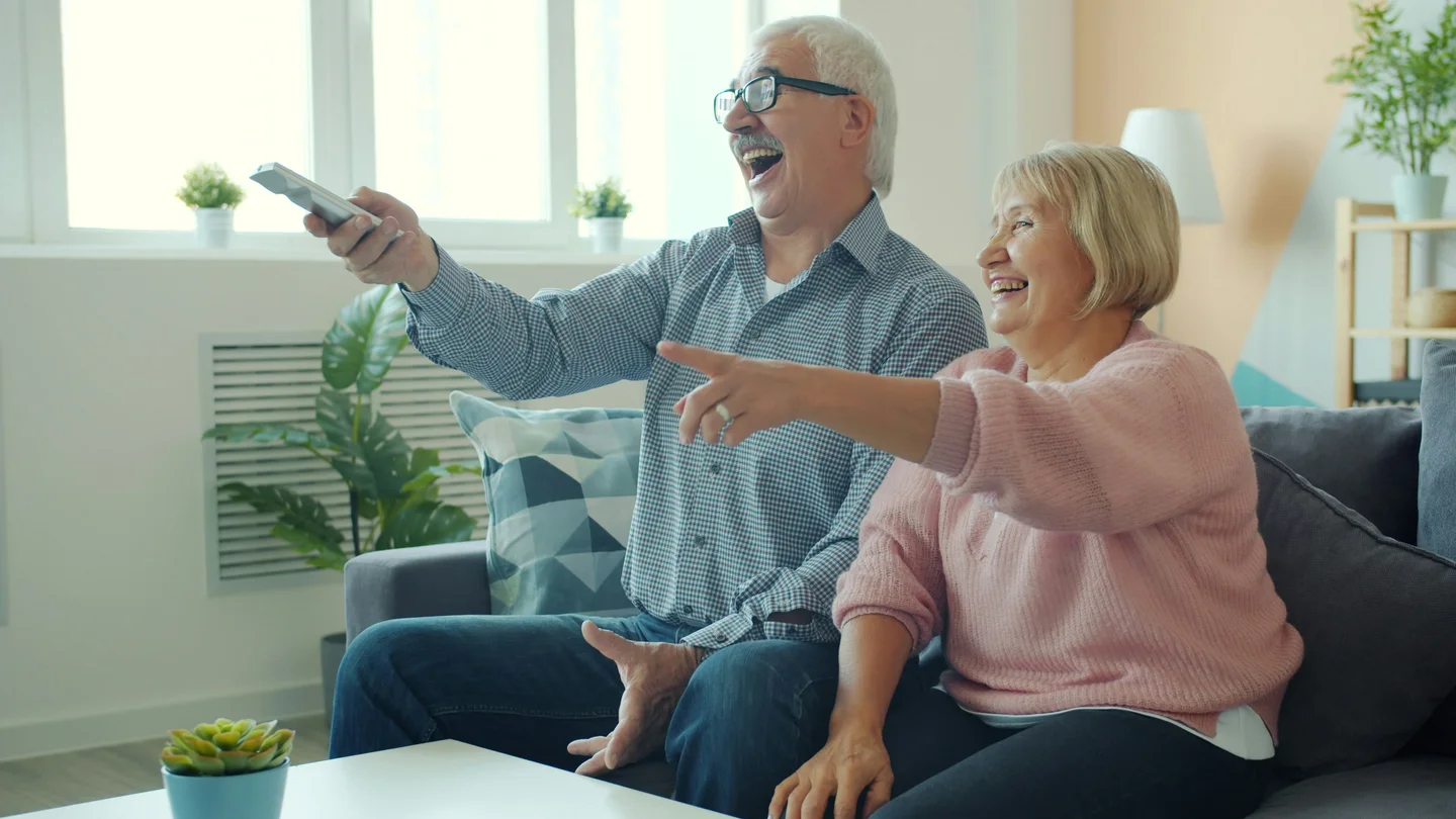 Un couple de grands-parents partage un moment devant la télévision